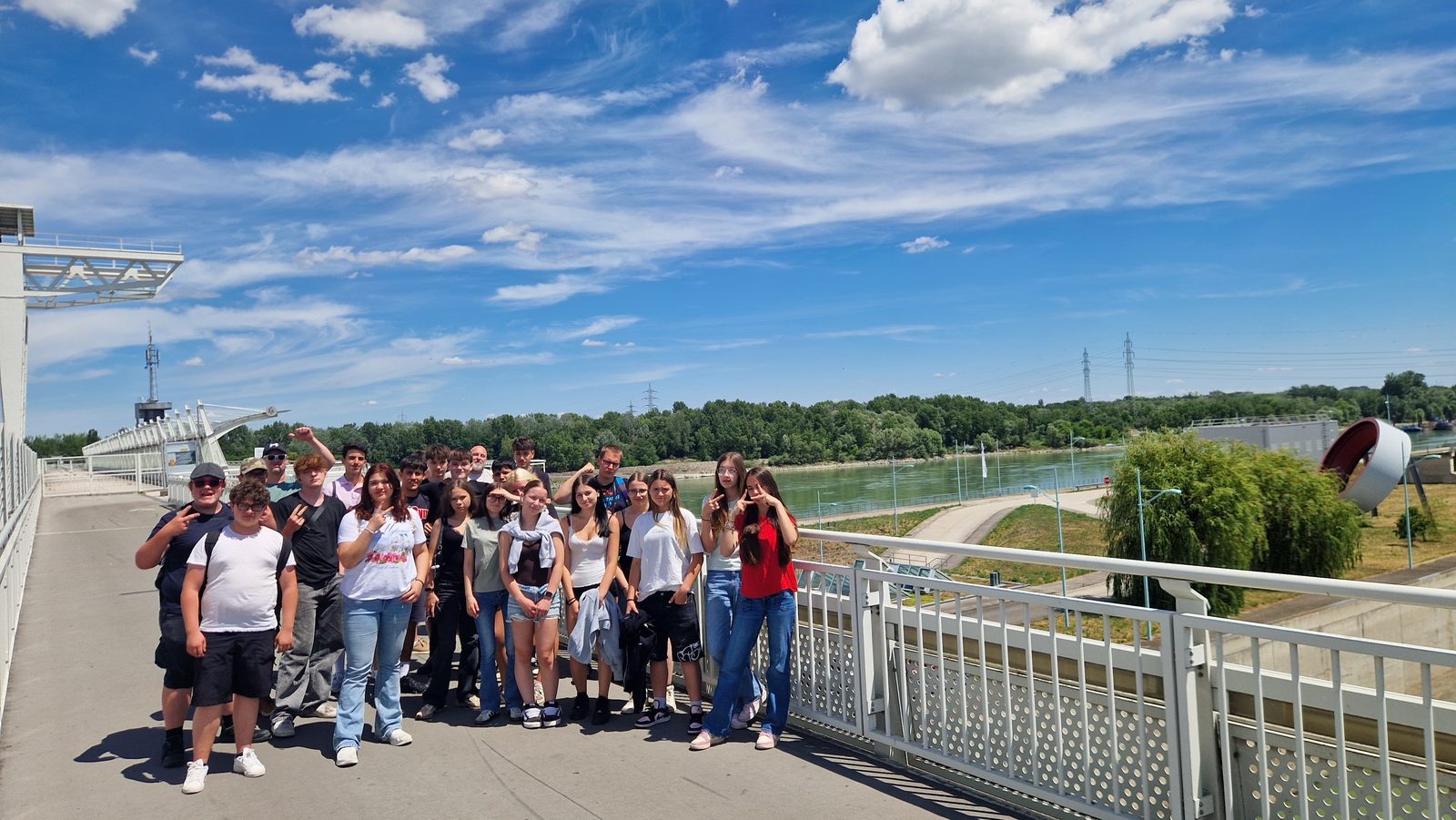 Gruppenfoto der Polytechnischen Schule Ebreichsdorf auf der Wehrbrücke des Donaukraftwerks Freudenau bei blauem Himmel