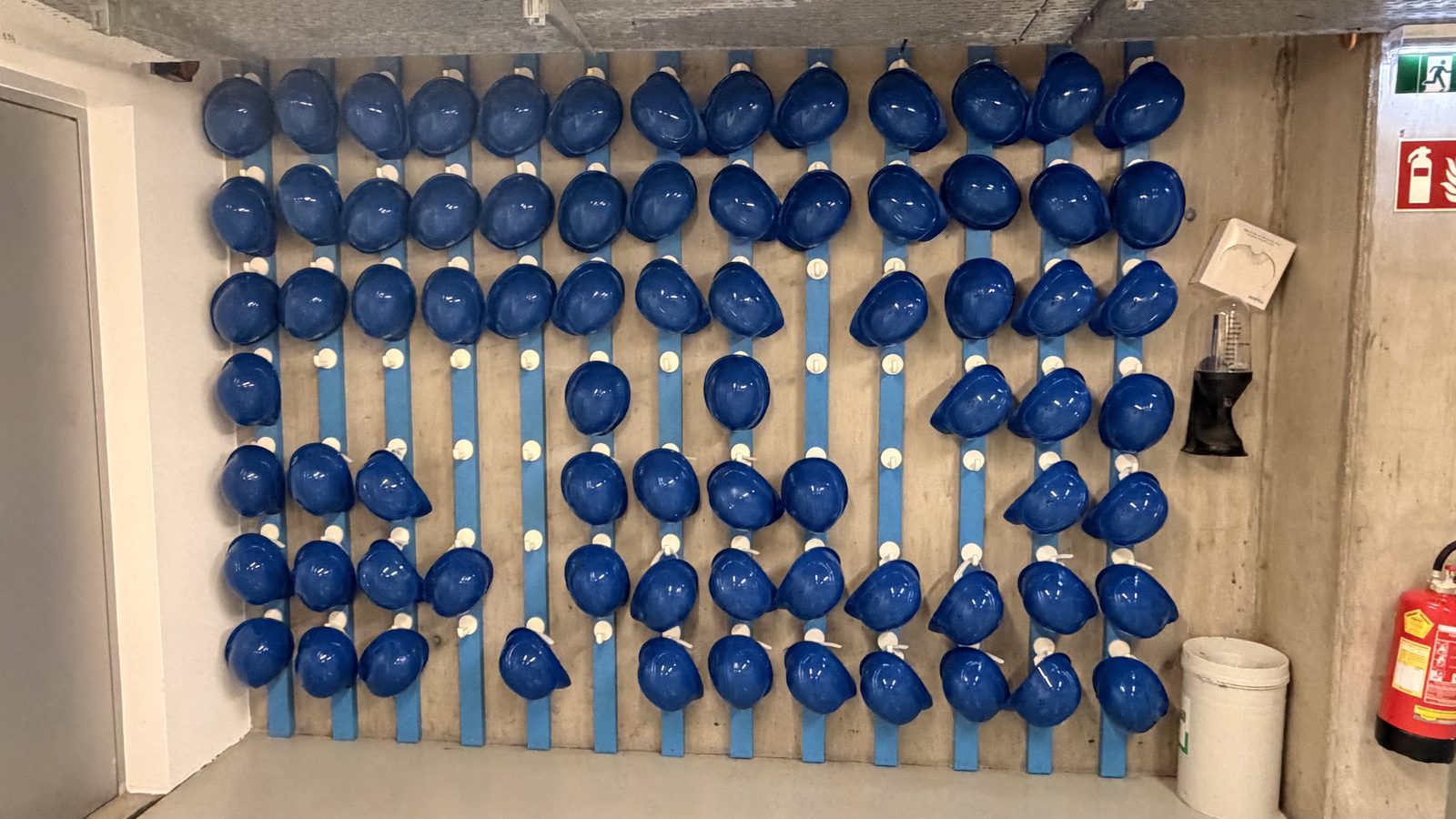 Wand mit zahlreichen blauen Schutzhelmen im Kraftwerk Freudenau