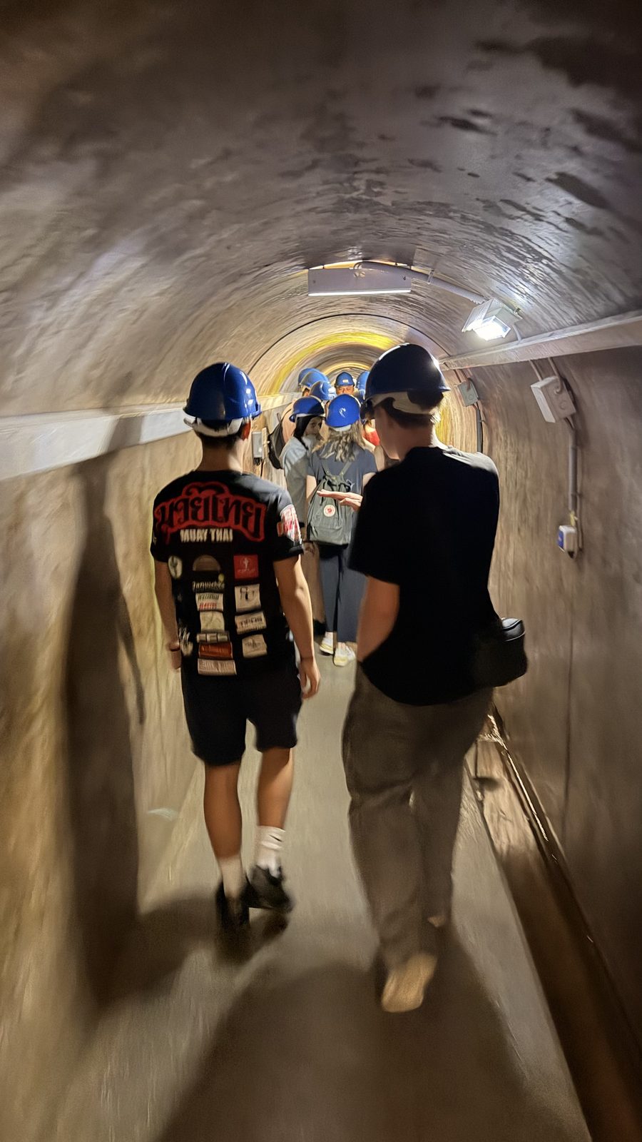 Schülergruppe geht durch einen niedrigen, feuchten Tunnel unter der Donau im Kraftwerk Freudenau