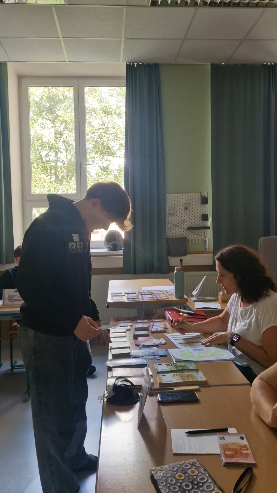Schüler zählt am Banktisch das Spielgeld des Planspiels Sozialstaat