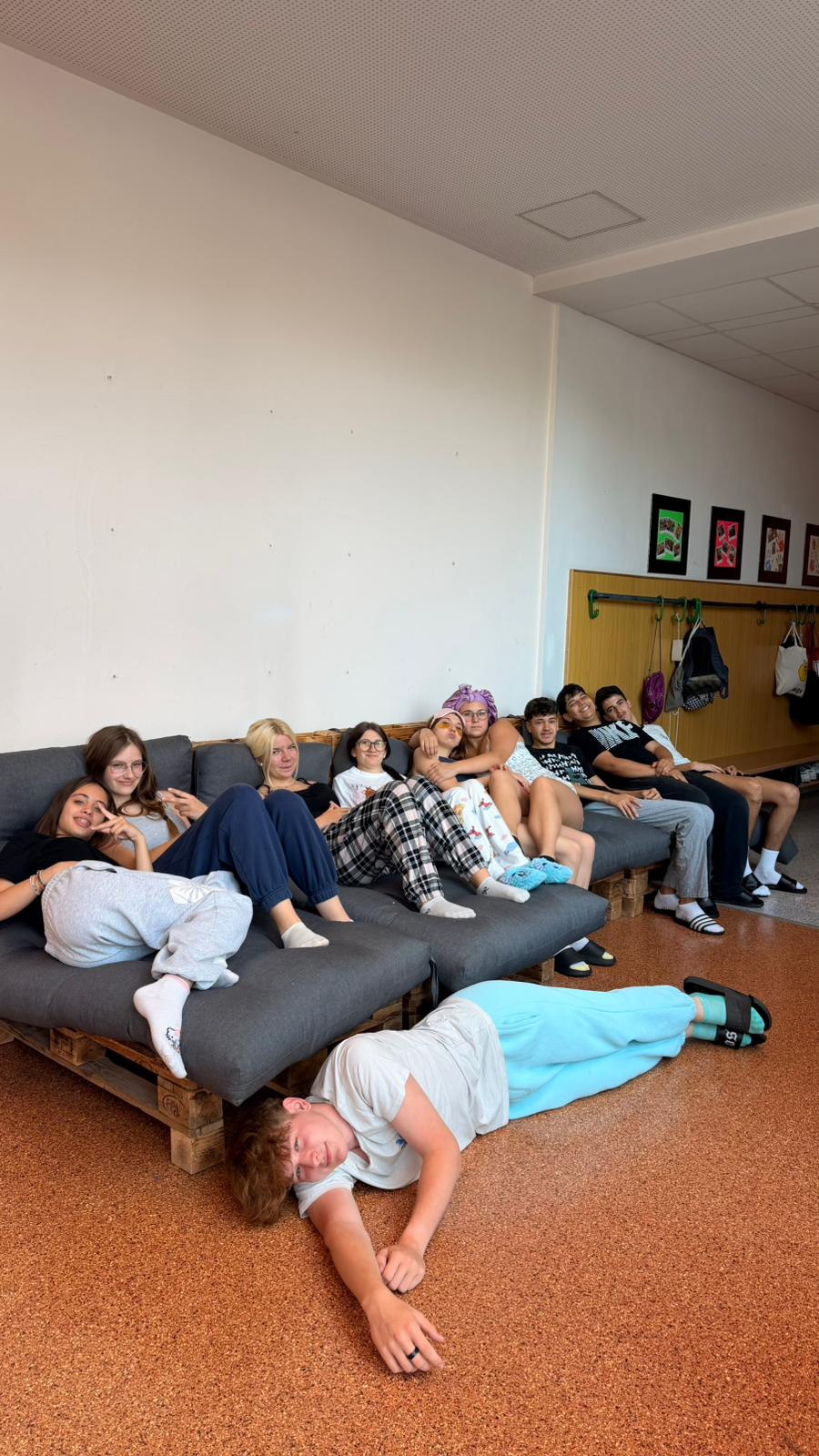 Klasse der Polytechnischen Schule Ebreichsdorf entspannt in Schlafanzügen auf einer Palettencouch